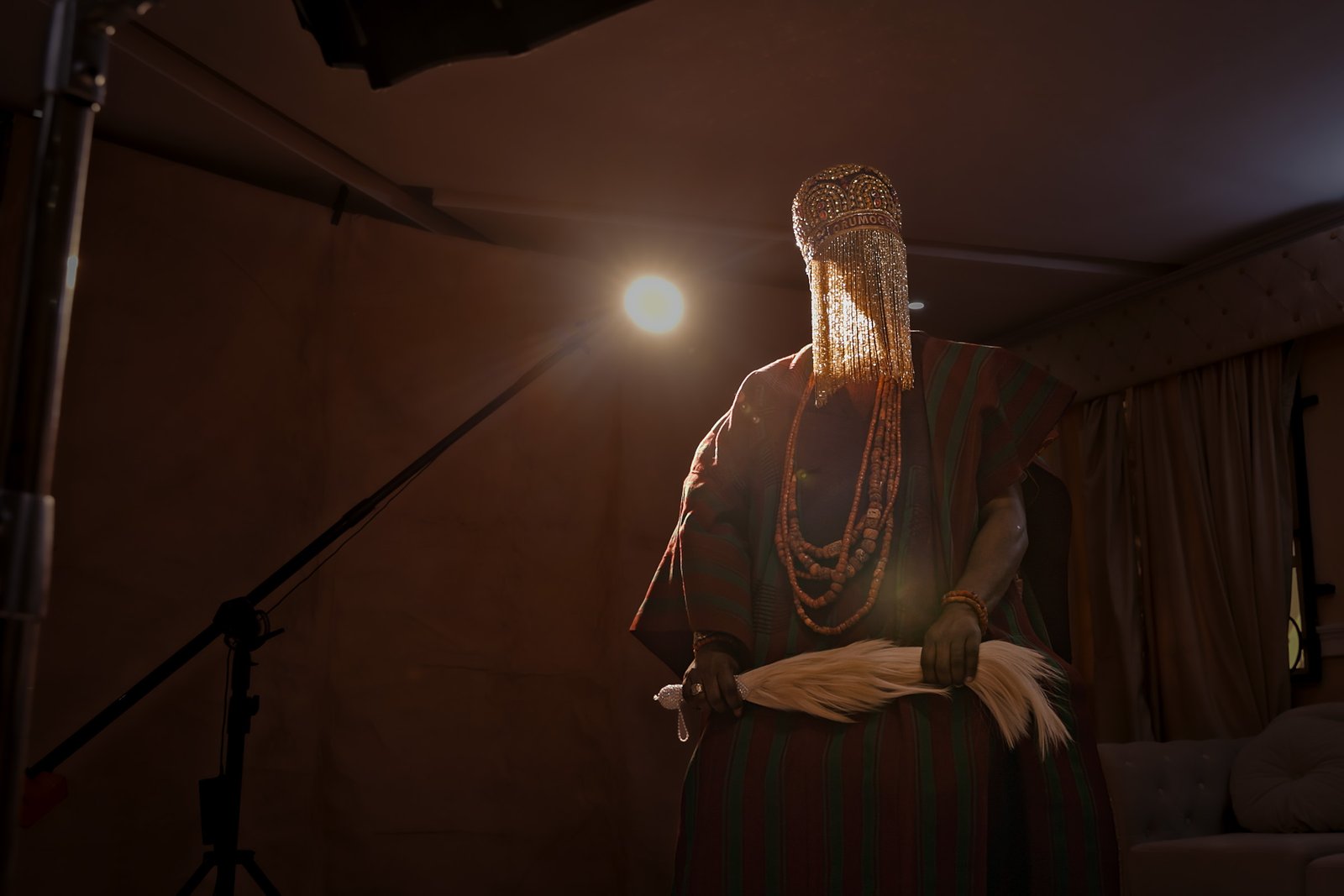 Oba Ghandi Olaoye standing during a behind-the-scenes production setup, illuminated by a film light.